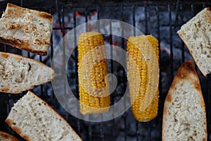 Closeup top view shot of salted corn grilled next to bread on the grates outdoors