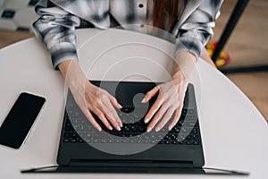 Closeup top view of unrecognizable female hands of business woman professional worker typing on laptop keyboard sitting