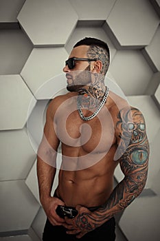 closeup topless portrait of Elegant handsome male model with fashion tattoo and a black beard standing and posing