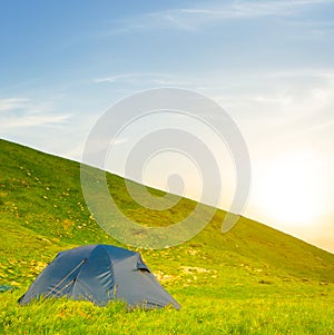 closeup touristic tent on green mount slope at the sunset