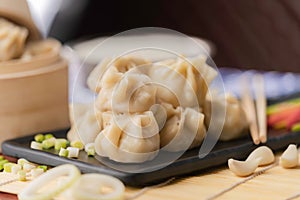 Closeup of a traditional Chinese food, Xiaolongbao, served in a black plate with green onions