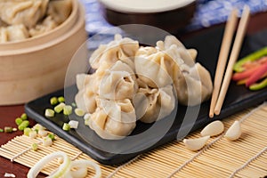 Closeup of traditional Chinese food, Xiaolongbao, served in a black plate with green onions