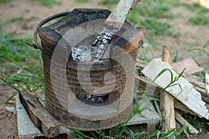 Closeup of traditional clay stove with ash and pile of firewood.