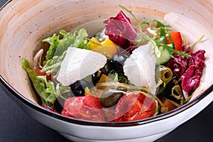 Closeup traditional greek salad with fresh vegetables, feta cheese, olives and olive oil in a bowl. Top view. Rustic style.