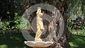 Closeup of a traditional greek style statue of a girl with a vase in Edwards garden