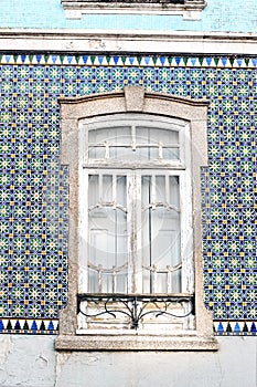 Closeup of traditional Portuguese house facade decorated by beautiful ceramic azulejo tiles Old white wooden window on