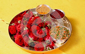 Closeup of a tray of red roses with powder spices and colorful rice on it