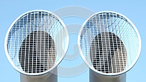 Closeup of tubes with ventilation grids in the light blue sky background