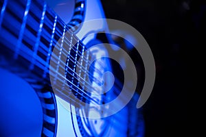 Closeup of a twelve string acoustic guitar lit up by blue light