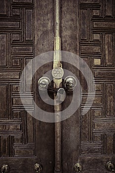 Two antique copper ornate door knockers over an aged wooden ornate door closed with chain and padlock, Mosque, Istanbul