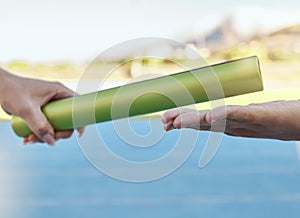 Closeup of two athletes passing a baton during a relay race on a running track. Active fit athlete handing the baton