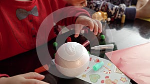 Closeup of two boys making handmade Christmas baubles, painting and decorating them with glitter. Winter holidays