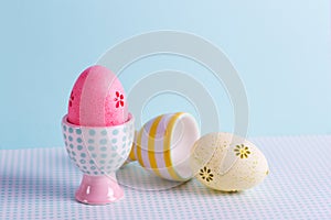 Closeup two colorful painted Easter eggs in vibrant modern egg stands on pastel blue background