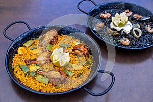 Closeup of two dishes of Paella and Arros negre served in a restaurant