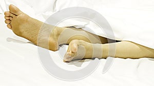 Closeup two feet on the bed a white background with sleeping at home relaxing in holidays.