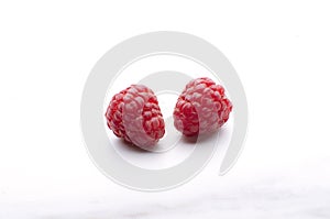 Closeup of two fresh and juicy rasberries on the white marble table