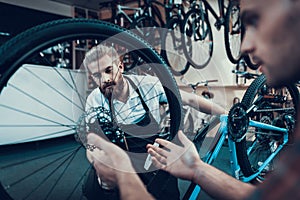 Closeup of Two Guys Fix Bicycle in Sport Workshop