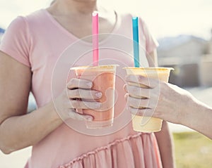 Closeup of Two hands holding healthy fruit smoothie drinks