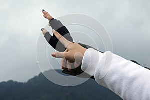 Closeup of two hands pointing at something or reaching out to the sky on gloomy sky background. Hope concept.