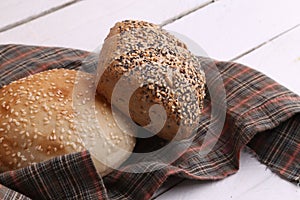 Closeup of two loaves of bread on a patterned cloth on a white wooden surface