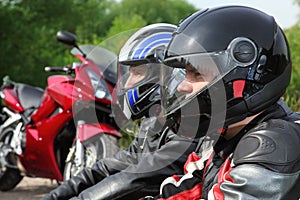 Closeup of two motorcyclists sitting near bikes