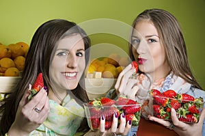 Closeup of two natural, beautiful girls eating strawberries