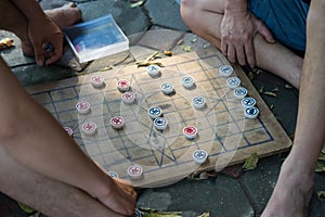 Closeup two old men playing Chinese chess on Hanoi sidewalk, Vietnam. Focus on chessboard