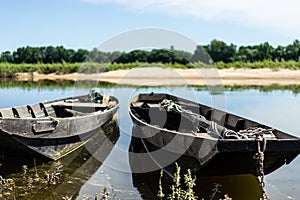 Closeup of two old row boats on a still water of Loire river by summer