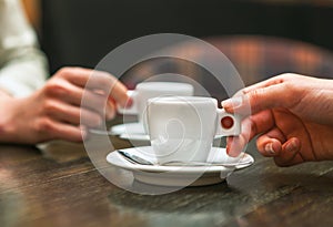 Two people holding cups of coffee sitting in cafeteria. photo