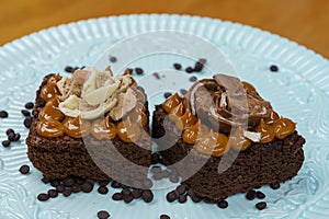 Closeup of two pieces of delicious brownie with manjar and chocolate on top on a white plate