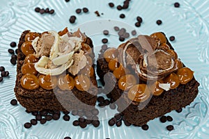 Closeup of two pieces of delicious brownie with manjar and chocolate on top on a white plate photo