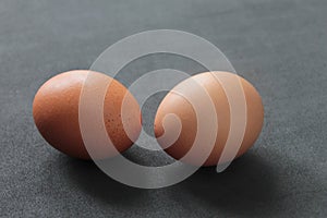 Closeup of two raw eggs on a gray table