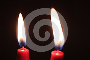 Closeup of two red candles burning in the dark