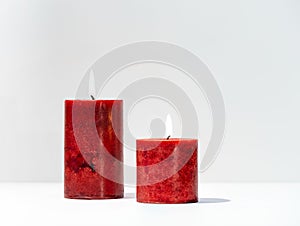 Closeup of two red candles burning on a white background with copy space