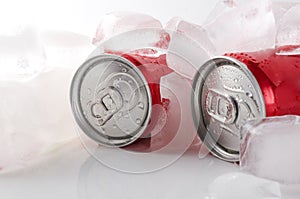 Closeup of two red cans of water and ice cubes on the white surface.Cold and fresh summer drink