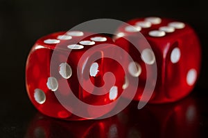 Closeup of a two red dice with a winning number on the top face on a black mirror surface