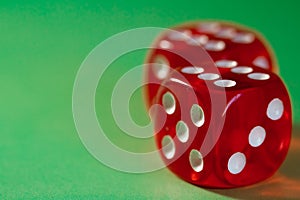 Closeup of a two red dice with a winning number on the top face on a green surface