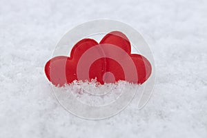 Closeup of two red little hearts on the snow.Concept of love and holidays mood