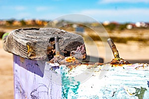 Closeup of two rusty screws and a piece of wood on edge of boat hull