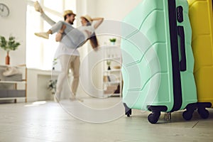 Closeup of two suitcases standing on floor with couple in love having fun in background