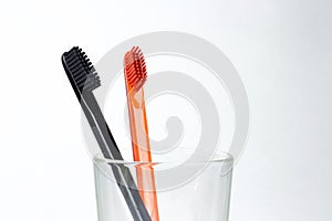Closeup of two toothbrushes in a glass beaker. For men and women