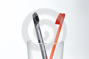 Closeup of two toothbrushes in a glass beaker. For men and women