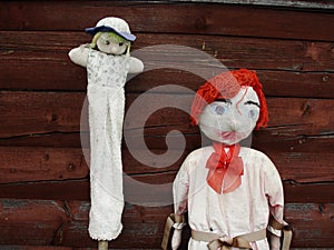 Closeup. Two. Two vintage, antique, handmade rag dolls, garden scarecrows, a red boy and a girl.