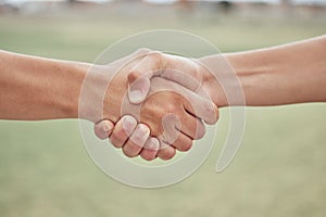 Closeup of two unknown baseball players shaking hands while standing on a grass field. Two sportsmen greeting or