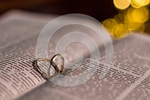 Closeup of Two Wedding rings on a Bible with bokeh background