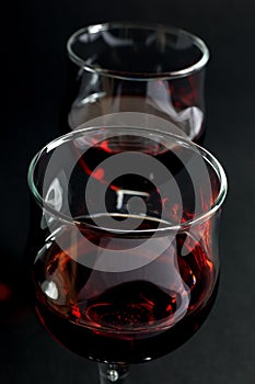 Closeup of Two Wineglasses Filled With Red Wine on Black