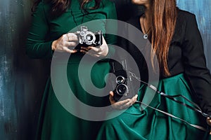 Closeup of two women`s holding vintage film cameras in studio