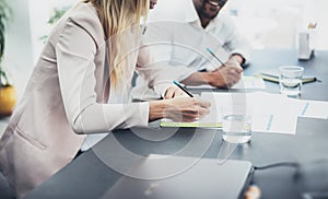 Closeup of two young coworkers working together on modern business project.Horizontal,blurred background