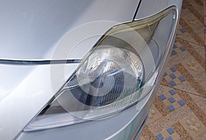 The closeup of the unclear headlight on the small sedan car