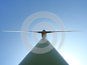 Closeup undershot of a wind turbine against a clear sky background